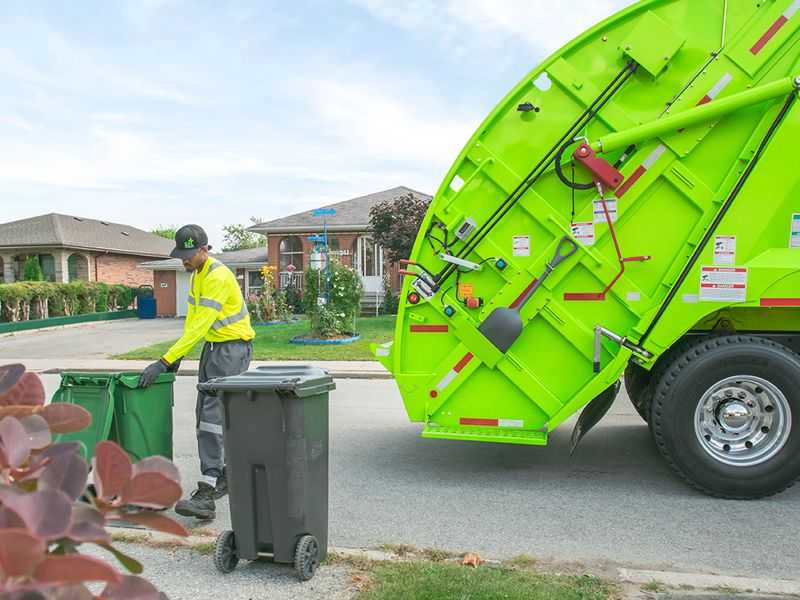 a waste collection employee loading a garbage truck