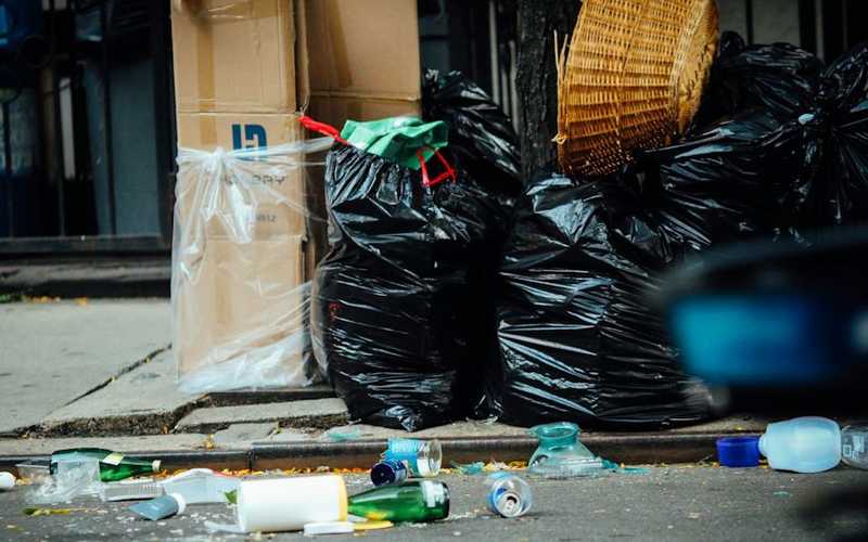 garbage lined up at curb with assorted garbage litter in the street